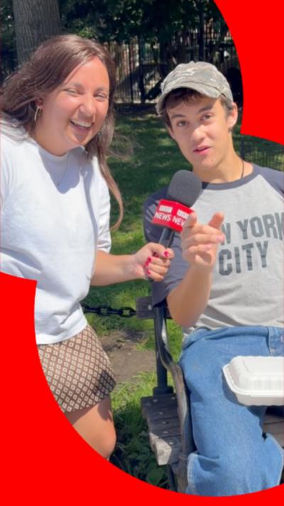 Yasmin Rufo smiles while a young man points at the camera wearing jeans and a New York City T-shirt.