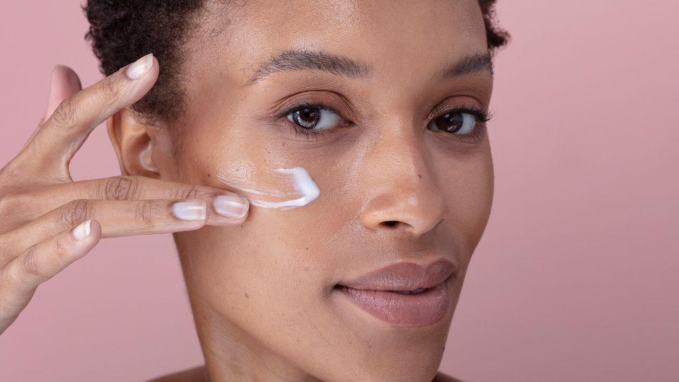 Woman applying cream to her face